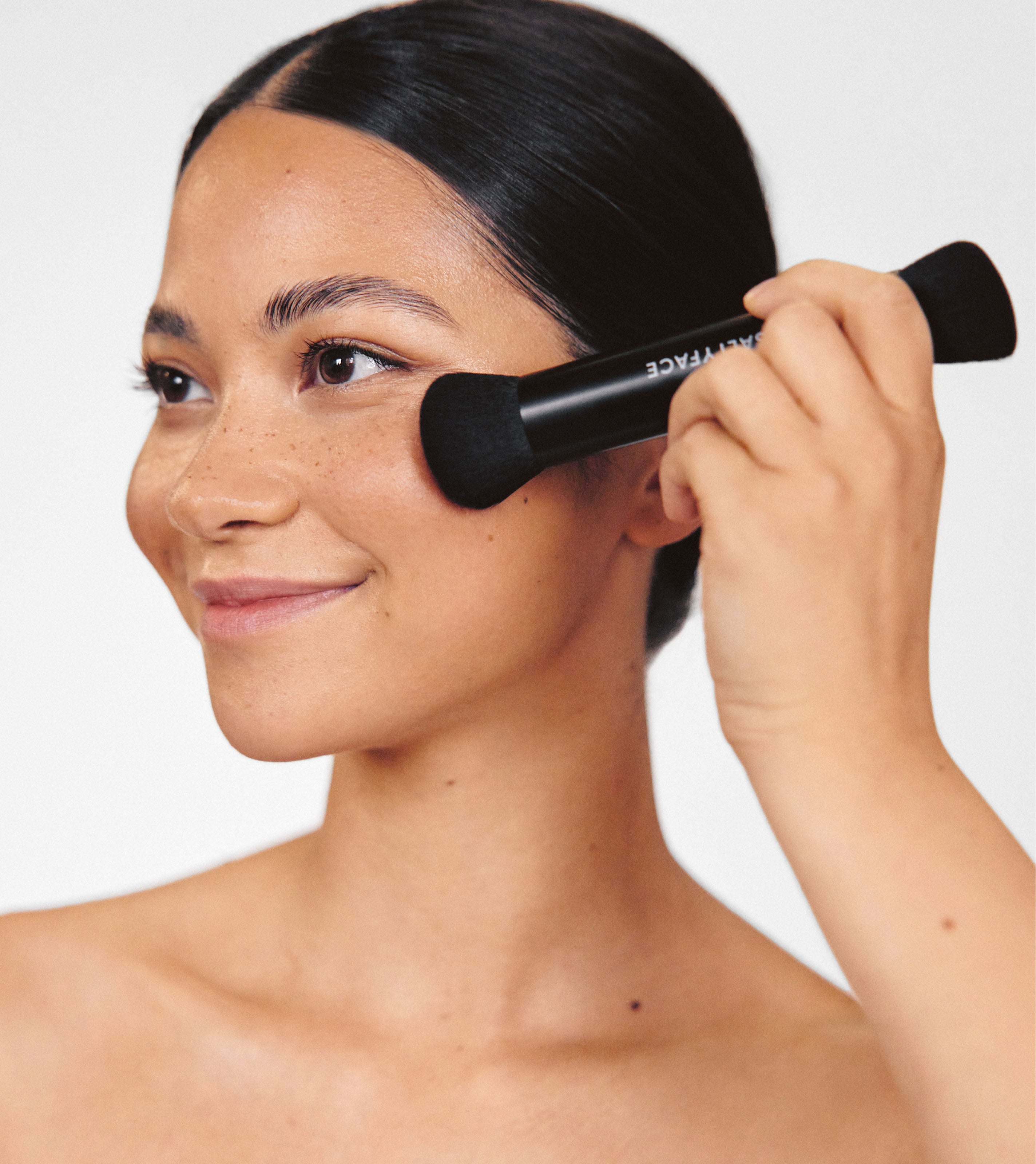 The large blending side of Saltyface's Brush No. 3 is shown blending in product on models cheekbone.